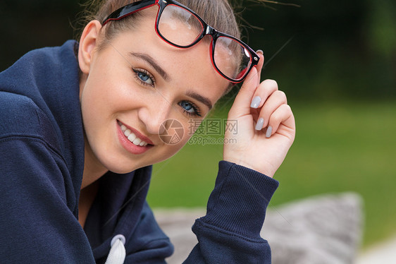 美丽的女孩,十几岁的女青年,蓝色的眼睛,外面戴着深蓝色的帽衫,笑着戴着红色黑色的眼镜图片