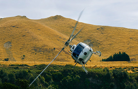架白色的直升机群山环绕的山谷里飞来飞去图片