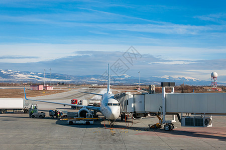 飞机,喷气式客机加油与走道附加行李被上传跑道围裙索菲亚机场,保加利亚,欧洲冬季与地面积雪图片