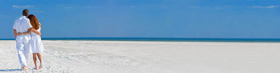 全景后视镜的男人女人浪漫的夫妇度假,穿着白色的衣服,走个荒芜的热带海滩上,图片
