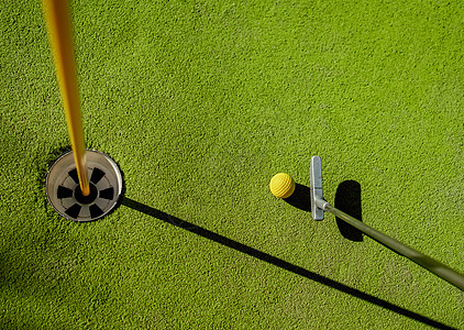 迷你高尔夫黄球与蝙蝠附近的洞日落图片