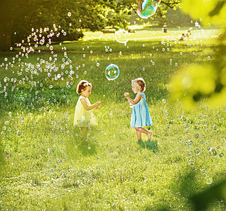 小女孩夏天新鲜的草地上吹肥皂泡图片