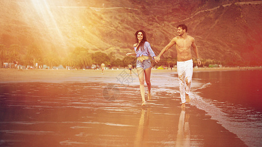 有吸引力的年轻夫妇沿着海边散步图片