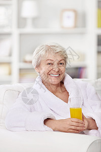 微笑迷人的女人穿着浴袍杯果汁图片