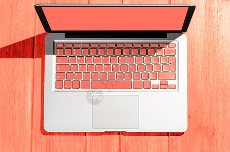 笔记本电脑与生活珊瑚色键盘木桌上的阳光明媚的天,上面看木制桌子上的笔记本电脑图片