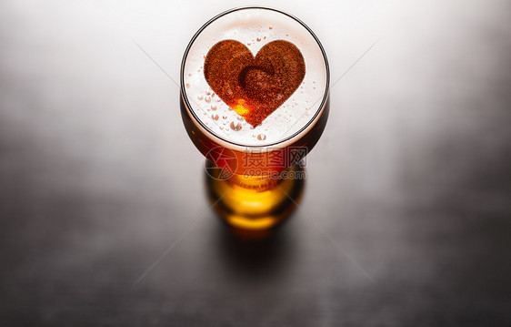 喜欢啤酒的黑色桌子上啤酒玻璃泡沫上的心脏符号,上面看喜欢啤酒的图片