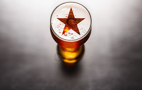著名的啤酒黑色桌子上啤酒玻璃泡沫上的星星符号,上面看著名的啤酒图片