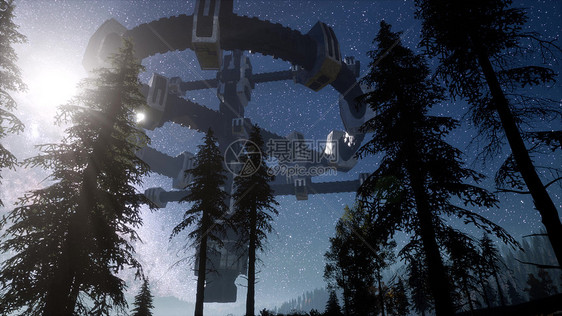 UFO夜间用光束盘旋森林上空图片