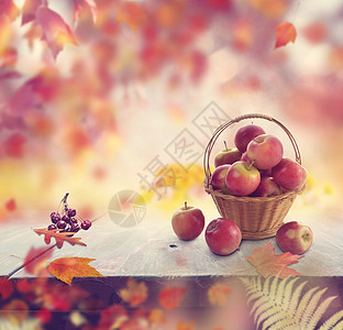 篮子里的红苹果秋天的叶子背景图片