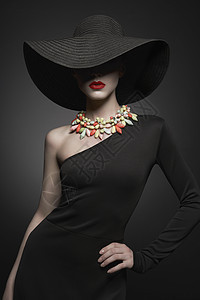 时尚肖像年轻感女士与美丽的黑色帽子晚礼服时尚优雅的女人与现代珠宝灰色背景上漂亮模特的工作室照片图片