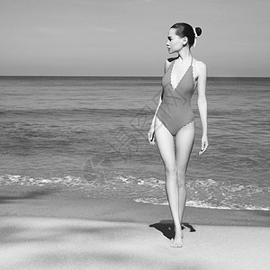 热带海滩上美丽感的女士时尚的女人,苗条完美的身材走海边模特姿势海洋附近的复古泳装放松年轻日光浴美女的肖像图片