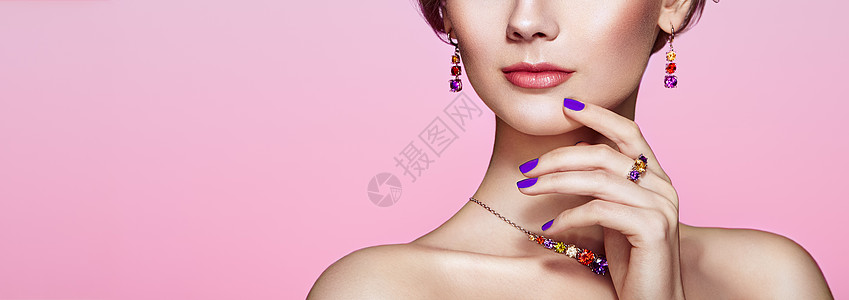 珠宝广告用珠宝描绘美丽的女人模特女孩用紫罗兰指甲修剪指甲美容配饰粉红色口红背景