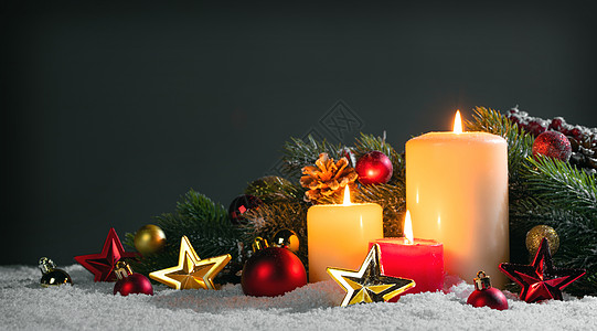 发光的星星装饰圣诞蜡烛与传统的装饰星星,红宝贝,松果绿色的树枝雪上带有装饰的圣诞蜡烛背景