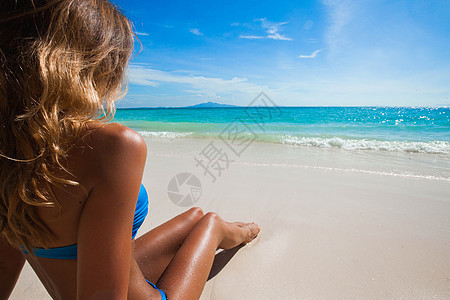 海滩上的女人坐沙滩上看着海洋,享受阳光暑假旅行,度假度假穿着比基尼的女孩蓝天下放松海滩上的女人看着海洋图片