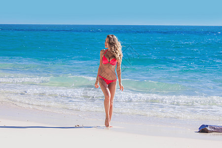 快乐的晒黑女孩穿着红色比基尼海边,蓝色的海水背景海边穿比基尼的快乐女孩图片