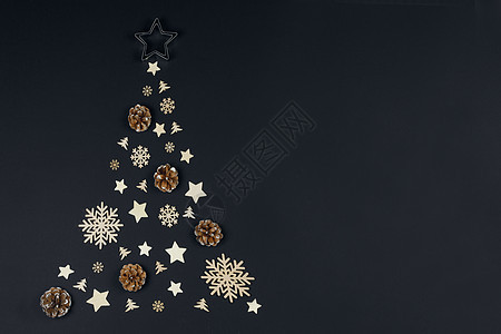 圣诞树由木制装饰松果制成,背景为黑色纸圣诞节假期平躺圣诞节假期图片