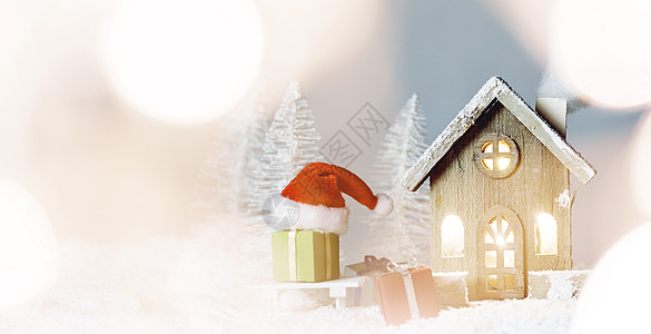 圣诞卡,舒适的小装饰房子,礼物圣诞老人的帽子,雪橇上的雪,童话冬天的冷杉森林背景下雪新年明信片文本圣图片
