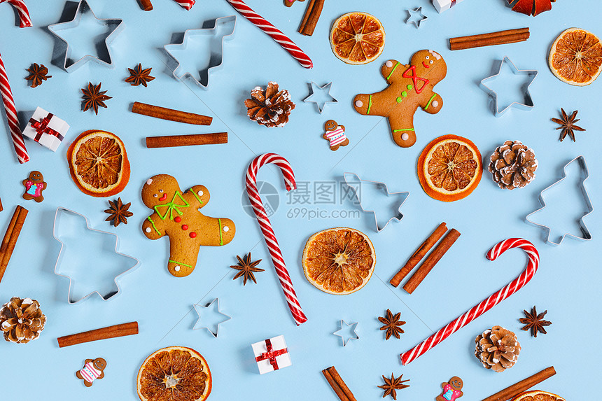 圣诞食品姜饼饼干,焦糖糖果,甘蔗,肉桂模具,八角橙片蓝色背景的礼物圣诞食品背景图片