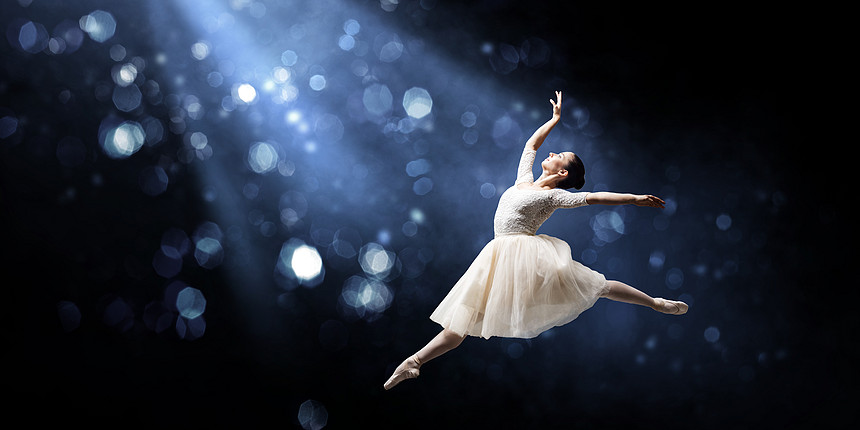 优雅的女舞者穿着白色的连衣裙黑暗的背景下跳芭蕾的舞者