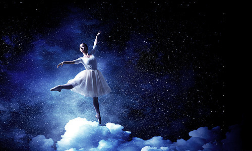 优雅的女舞者穿着白色的连衣裙,黑暗的背景下跳芭蕾的舞者图片