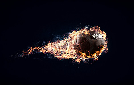 橄榄球黑暗背景下的火焰中美国足球比赛的图片
