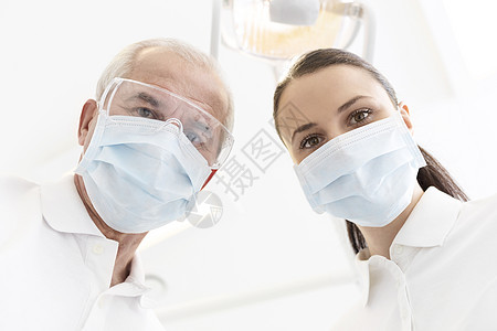 牙科诊所戴口罩的同事的低角度肖像图片