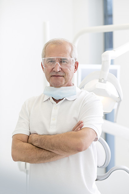 牙科诊所交叉双臂的自信牙医的肖像图片