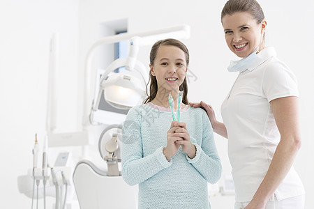 牙科诊所微笑的牙医带牙刷的女孩的肖像图片