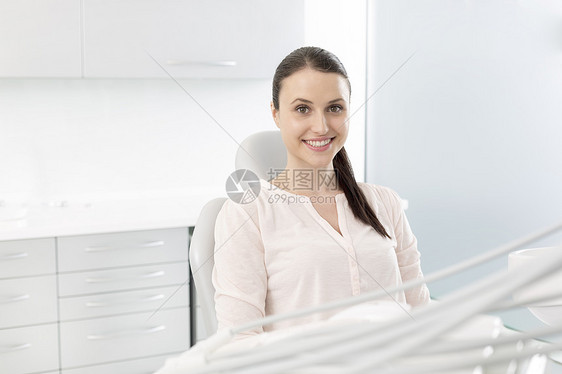 微笑的女病人坐诊所的椅子上的肖像图片