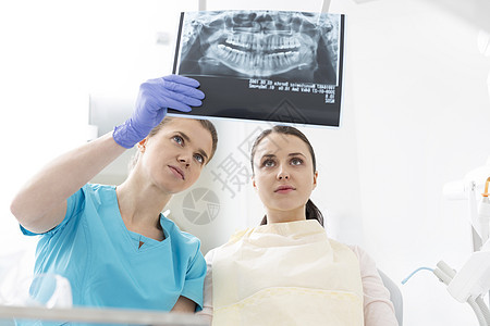 牙科诊所向妇女展示X光的女牙医图片