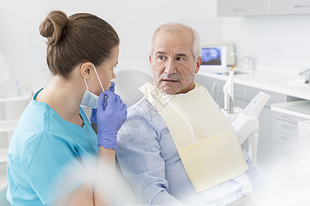 牙医牙科诊所与惊讶的高级病人交谈图片