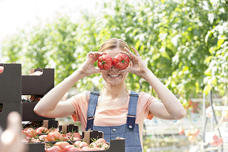 微笑的女人站农场里玩西红柿图片