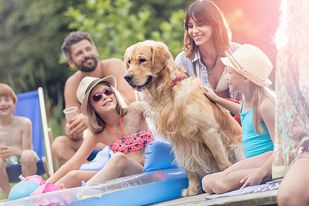 微笑的女孩抚摸金毛猎犬,而坐码头上的家人图片