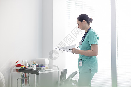 中年护士检查医院剪贴板上的医疗报告图片