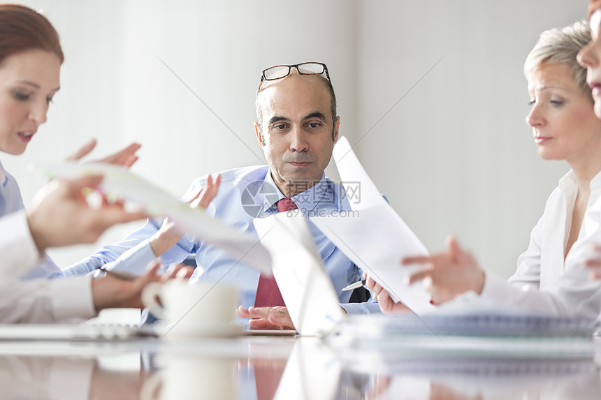 商人看着同事会议室讨论文件图片