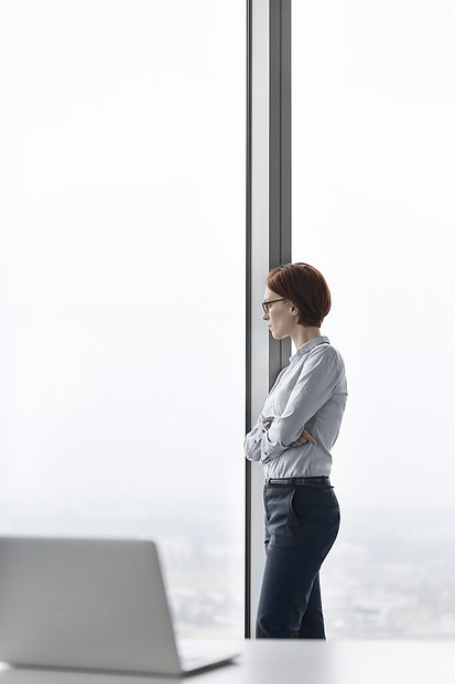 有思想的年轻女商人办公室透过窗户看的侧面