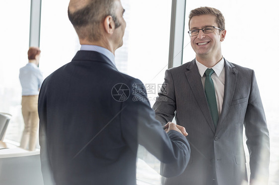 微笑的商人办公室开会时与会议室的同事握手图片