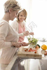 微笑成熟的朋友厨房准备饭菜图片