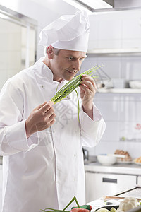 自信成熟的厨师站餐厅厨房闻着新鲜的葱束图片