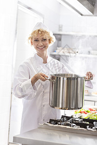 微笑的厨师餐厅厨房的炉子上着钢锅的肖像图片