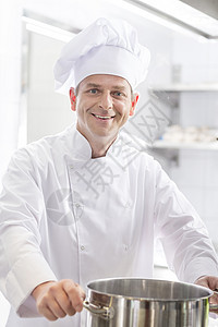 餐厅厨房用钢制炊具微笑成熟厨师的肖像图片