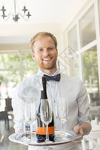 自信的年轻侍者餐厅端酒的肖像图片