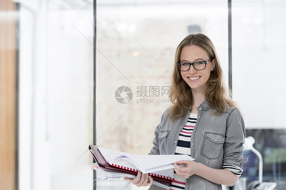 年轻女商人办公室持有文件的肖像图片