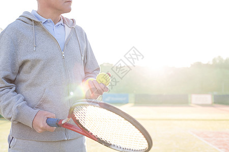 成熟男人的中段,着网球球拍着晴朗的天空图片