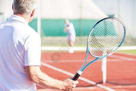 网球场上朋友起玩的成熟男人着球拍的后视镜图片