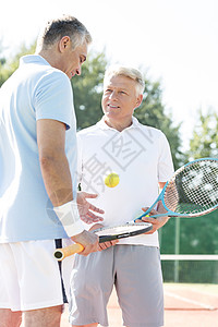成熟的男人夏天的周末,边站网球场上,边说话图片