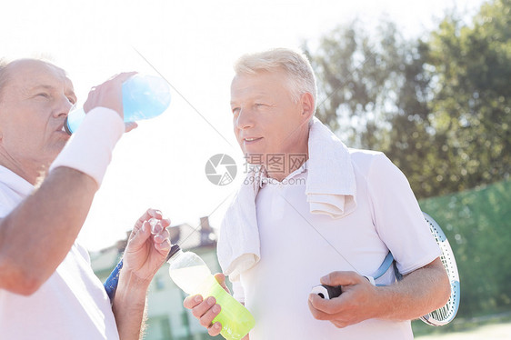 成熟的男人,看起来资深的朋友,夏天站网球场上喝酒图片