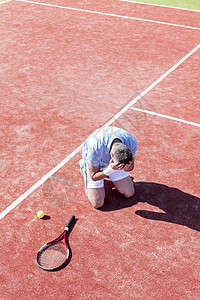 整个长度失望的成熟男子,头手,而跪网球拍红场夏天图片
