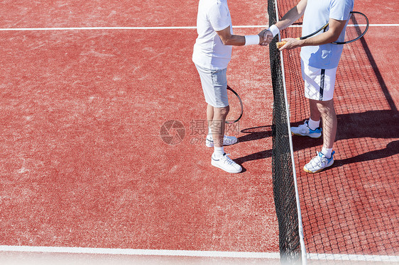 比赛中,红场上站网球网旁的低段男子握手图片