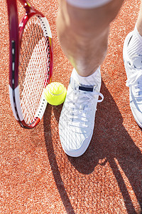 低段老人站红色球场上,着网球拍球图片